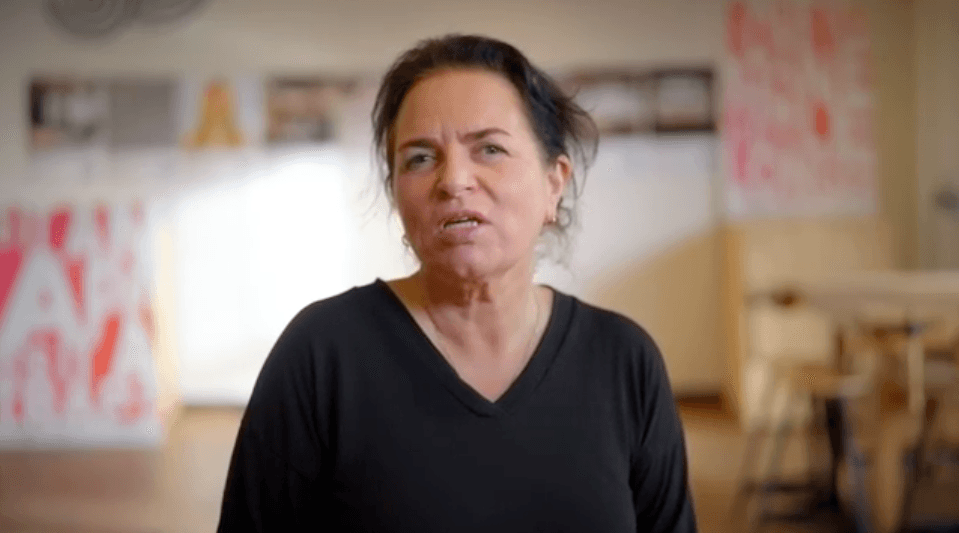 Screenshot van interview met Marleen Stikker in Waag Futurelab. Op de achtergrond zie je de paars-roze borden van de Fix Your Phone Shop.