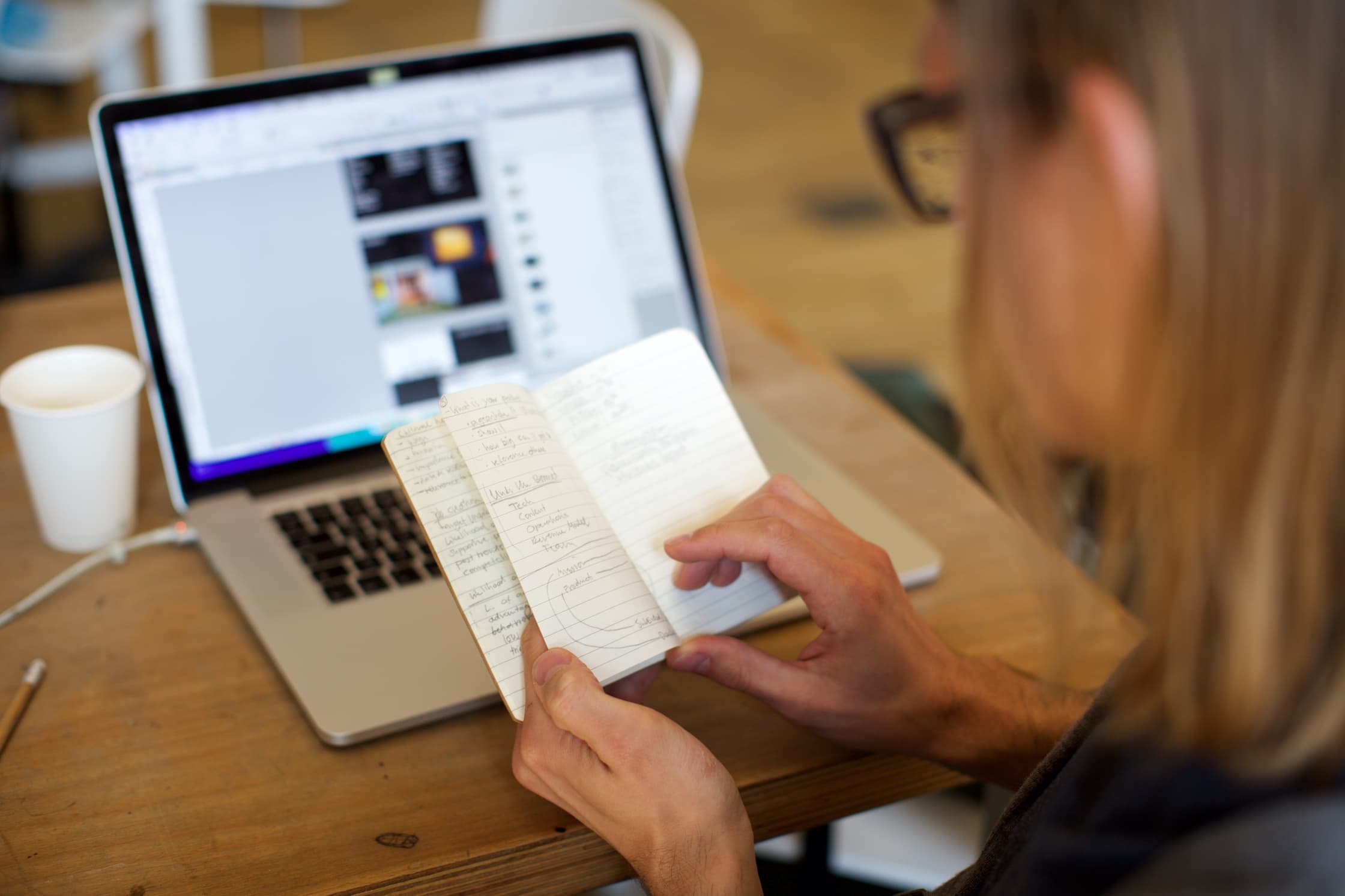 Mevrouw met een boekje en haar laptop op de achtergrond
