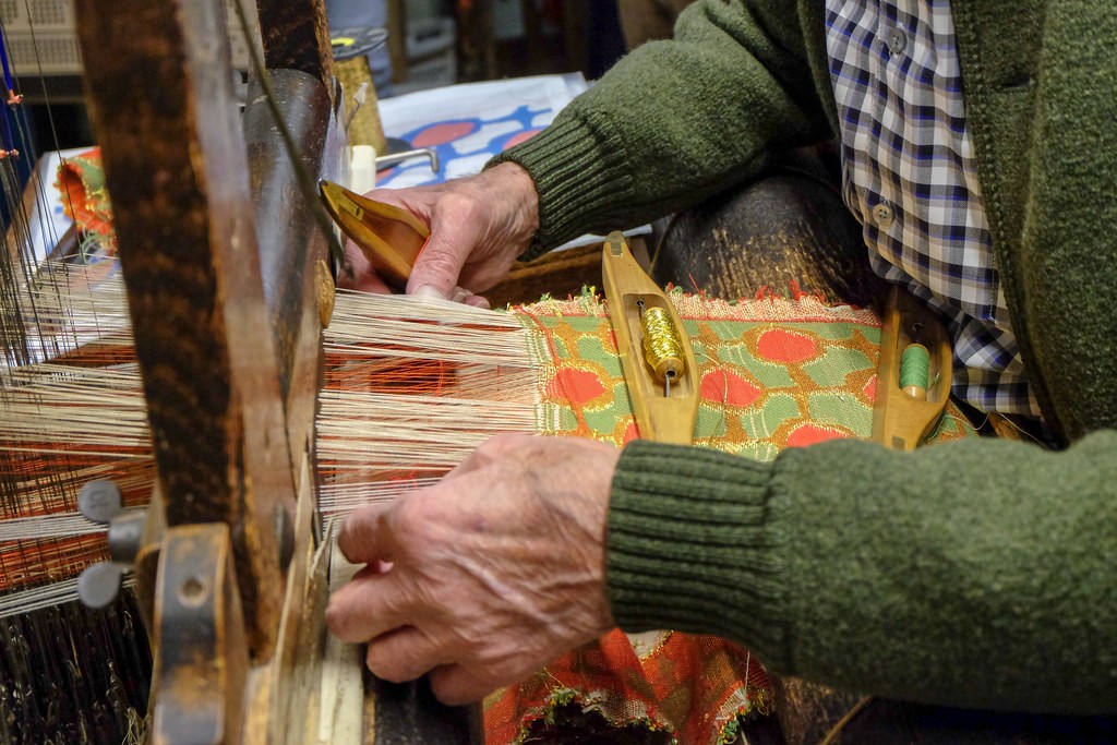 Een man weeft jacquard in het Haus der Seidenkultur