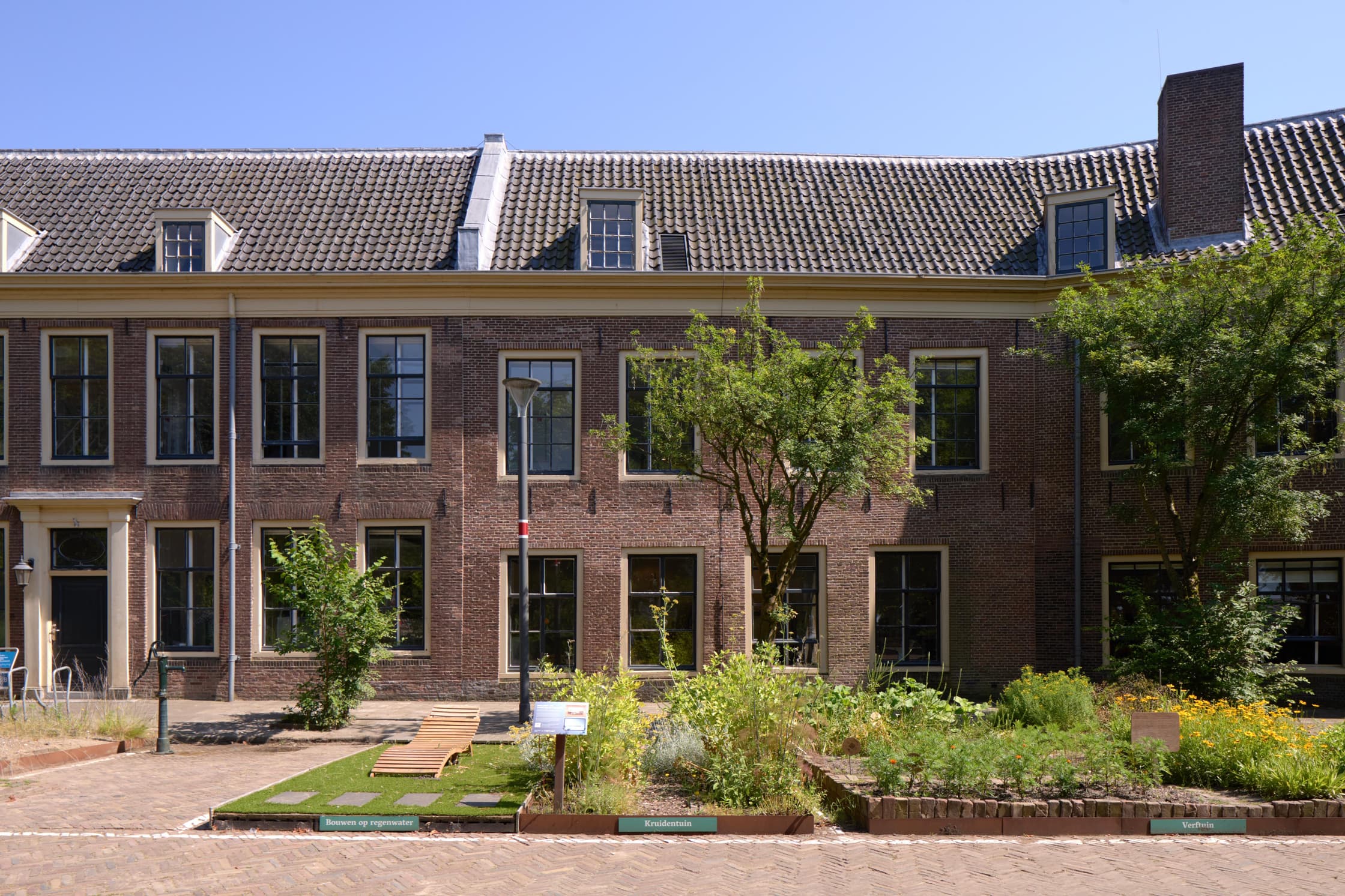 Foto van de verftuin van Waag Futurelab op het Marineterrien in Amsterdam. Op de voorgrond de verftuin, met erachter monumentale gebouwen.